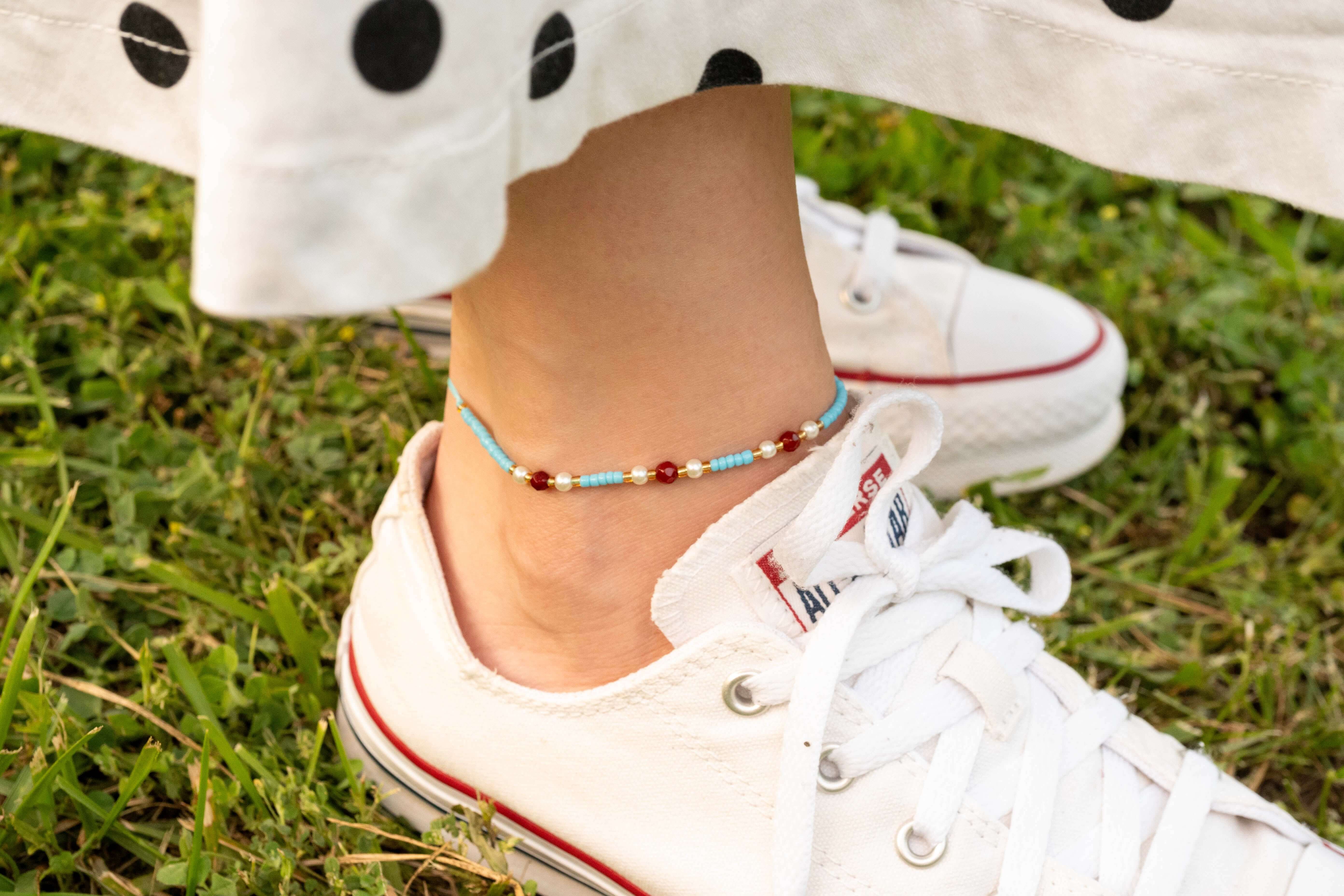 Бохо гривна за глезен с цветен конец и мъниста в лятна обстановка на зелена трева.