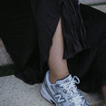 Сребърна Гривна за Глезен Нишка S925 носена с маратонки New Balance на стълби.