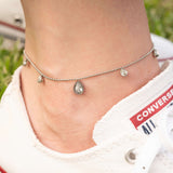 Гривна за глезен с блестящи циркониеви камъни, носена с спортни обувки на зелена трева.