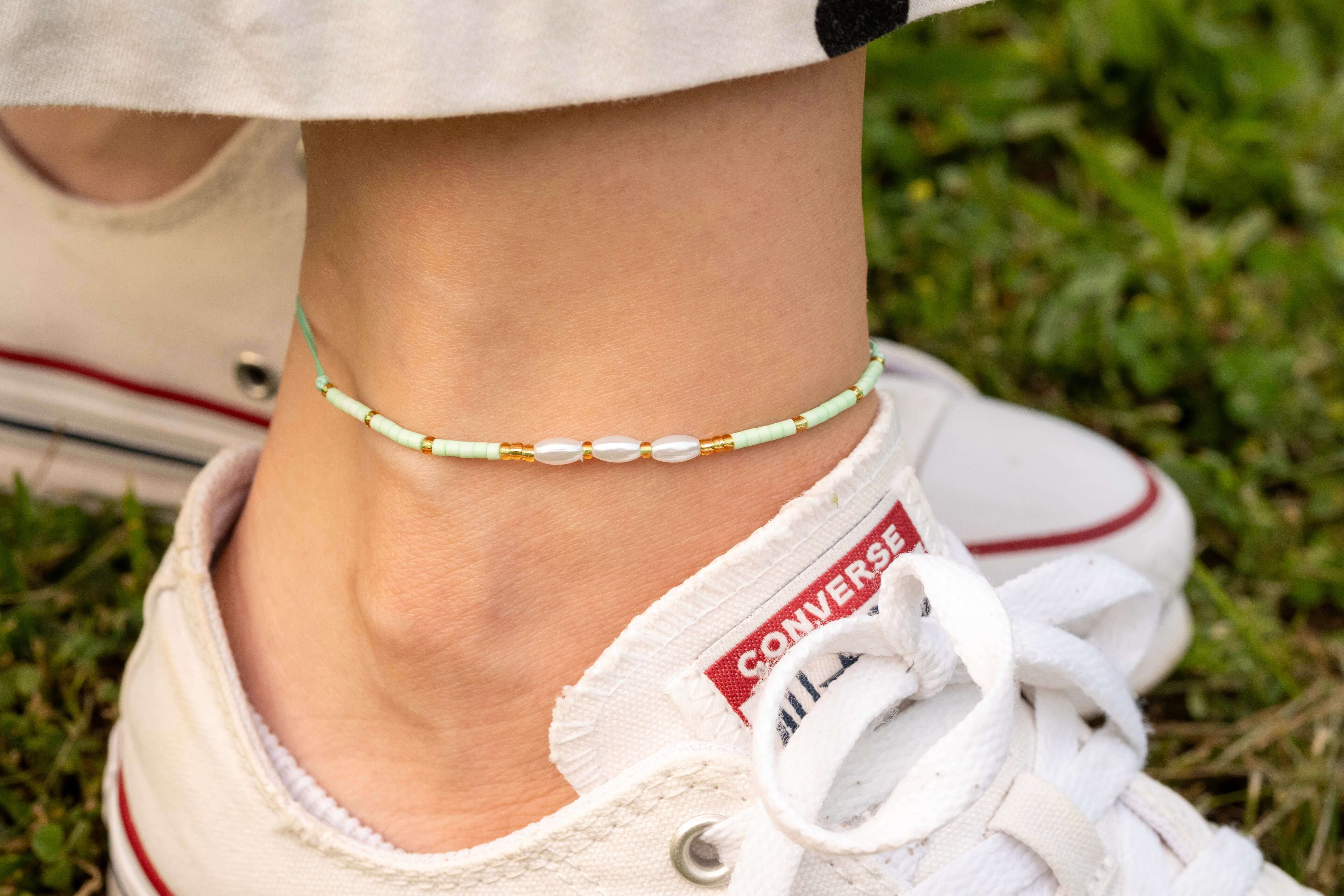 Ръчно изработена бохо гривна за глезен с перлички и мъниста, носена на гол крак с бели обувки.