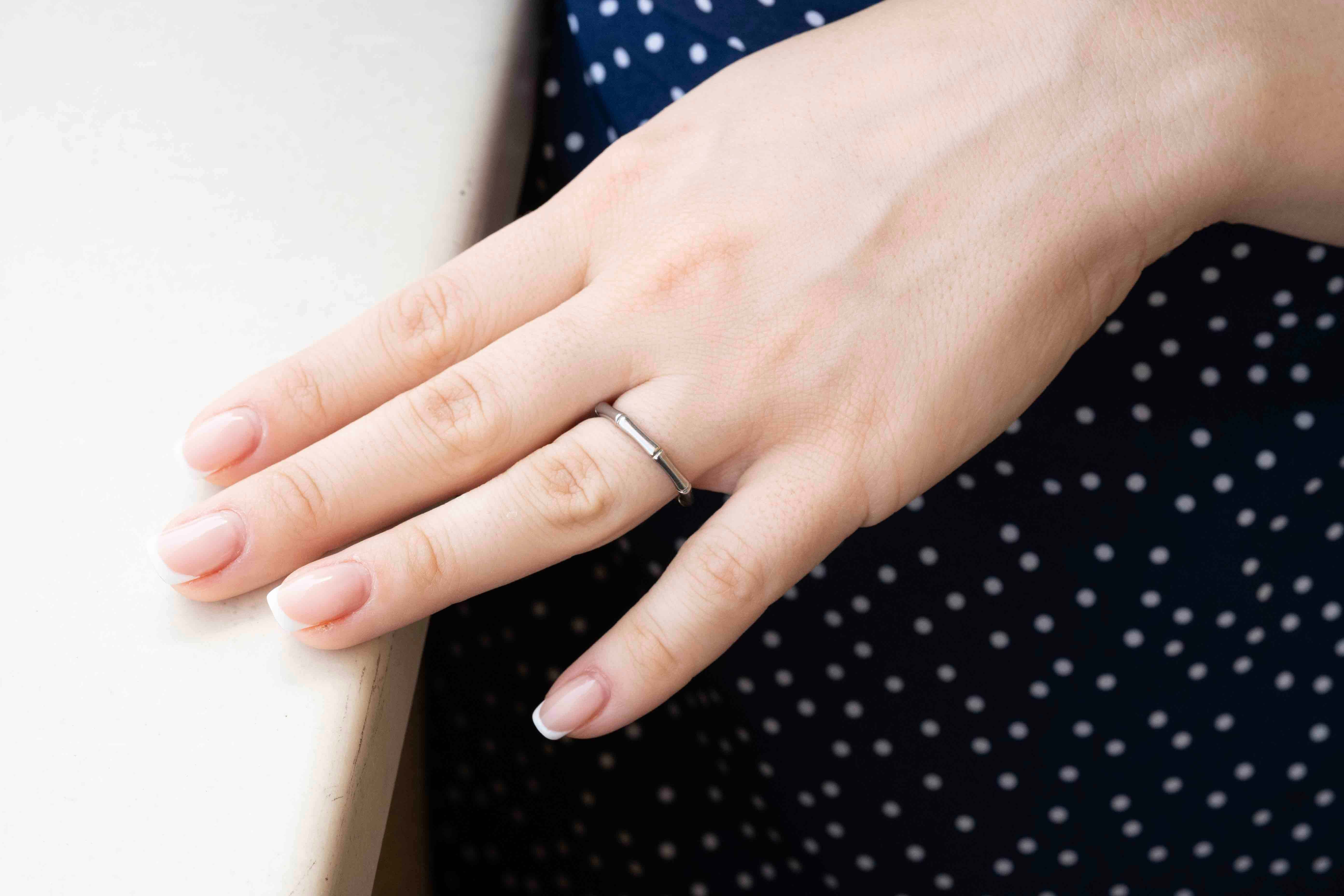 Елегантен пръстен от стомана Bone, показан на ръка с нежни нокти, идеален за ежедневно носене.