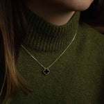 Колие One Clover от сребро с 14К златно покритие, носено от жена с зелена жилетка.