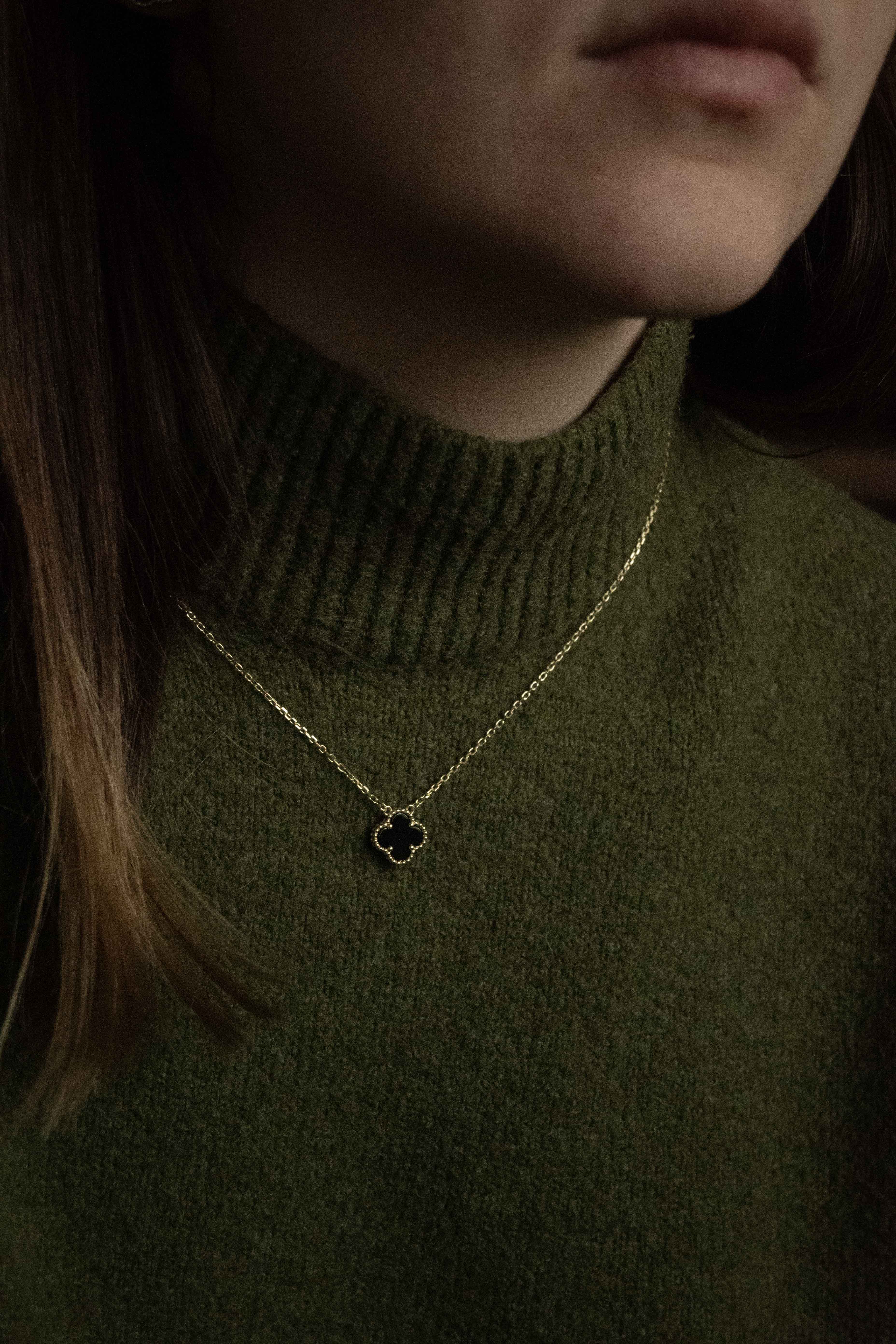 Колие One Clover от сребро с 14К златно покритие, носено от жена с зелена жилетка.
