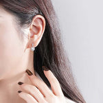 Сребърни обеци Разкош S925 с кристали, носени от жена, с дълга тъмна коса.