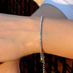 Гривна с инкрустирани камъни, носена на ръката, показваща елегантен дизайн и блясък.