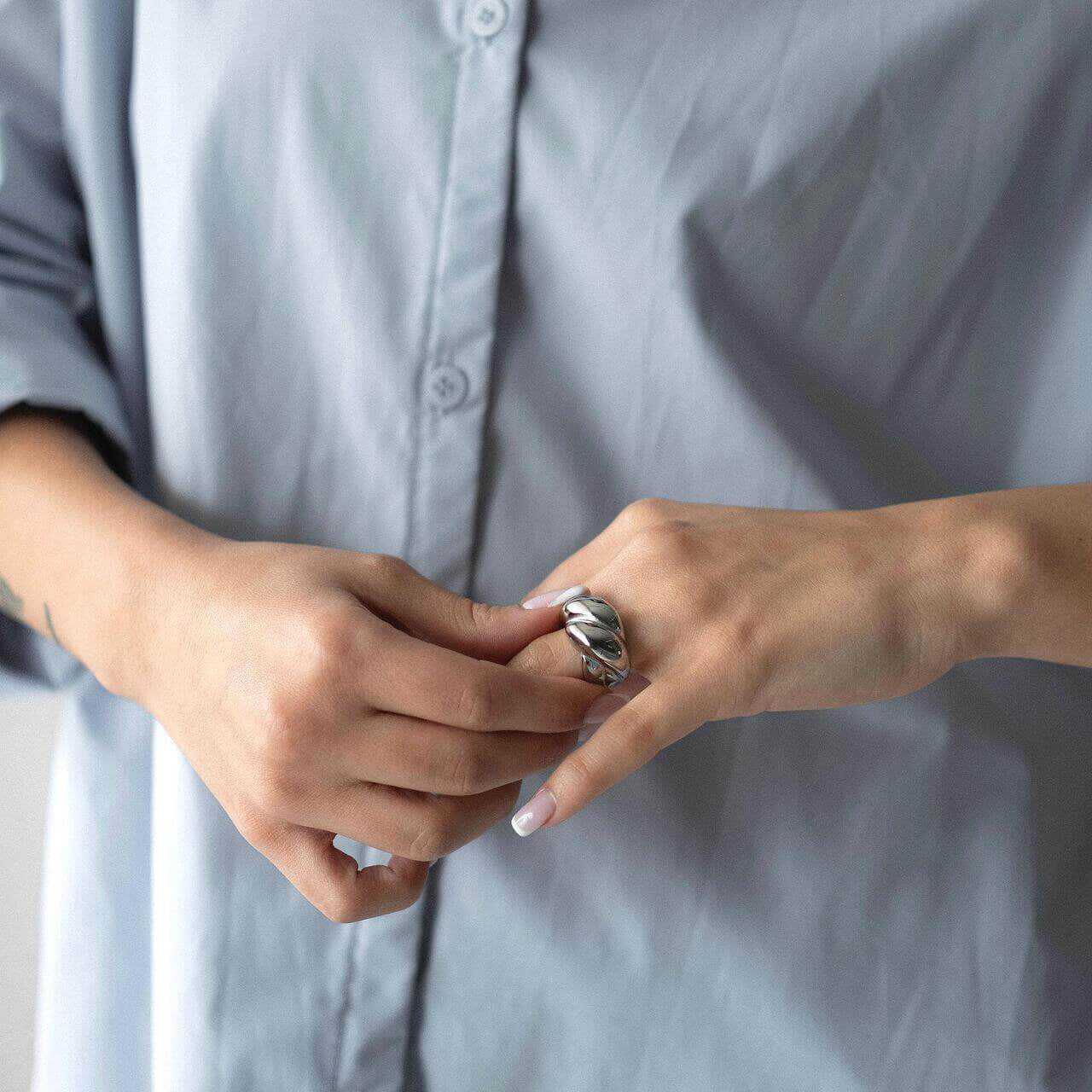Woman wearing a chunky ring with 18K gold plating over a pale blue shirt, showcasing stylish jewelry.