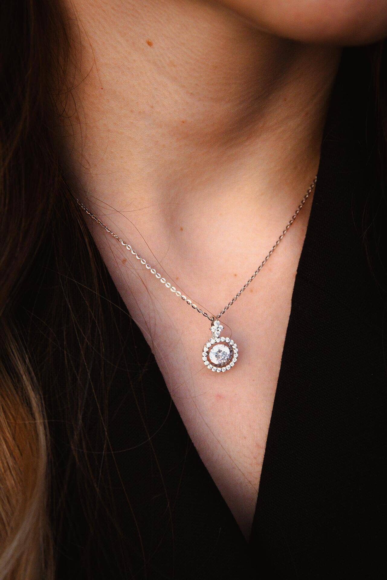 Елегантно сребърно колие с блестящ камък, носено от жена, подходящо за специални поводи.