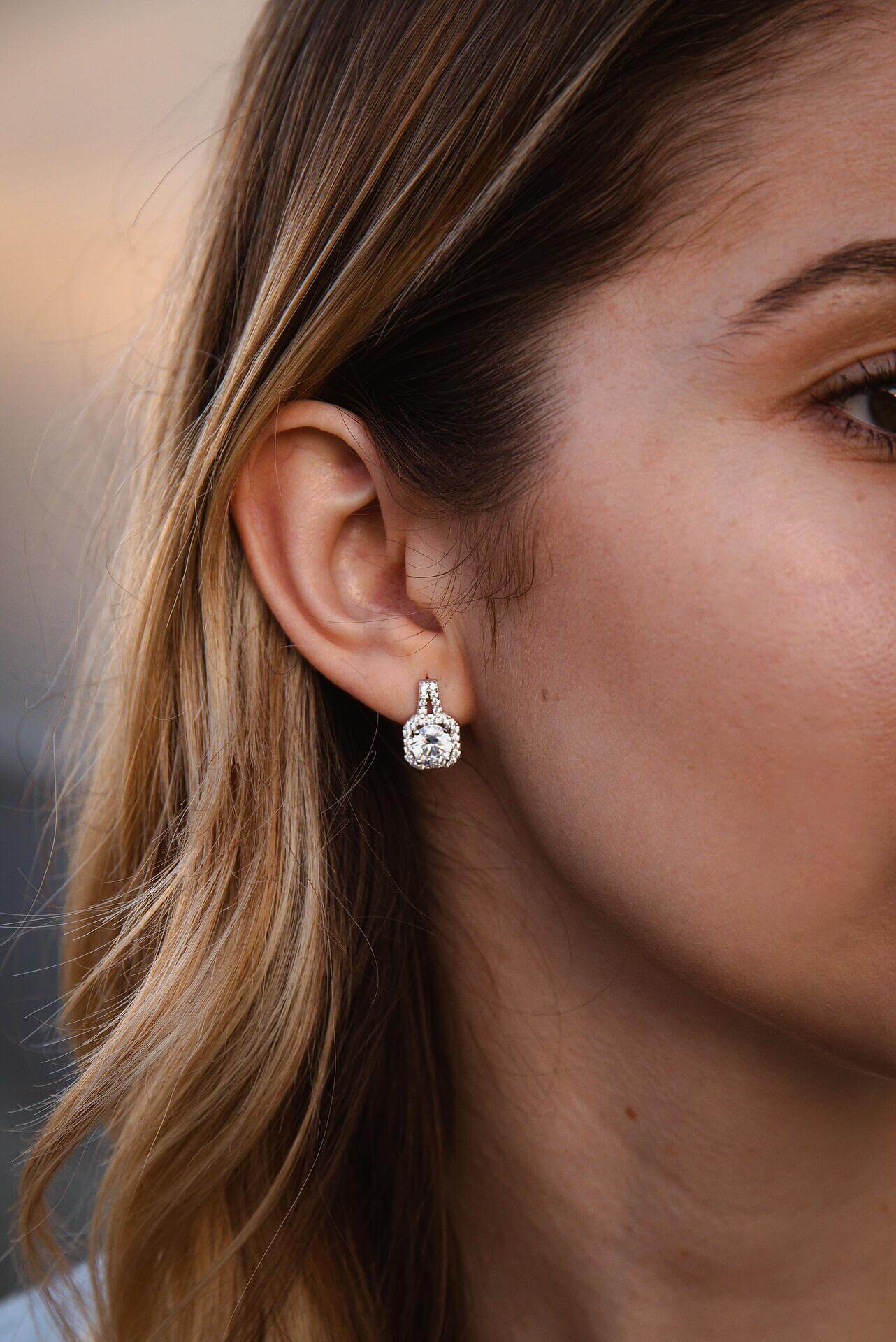 Елегантни обеци с блестящи камъни, изработени от сребро S925, носени на дамско ухо.