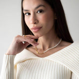 Stylish woman wearing a pearl and chain necklace with 18K gold plating, showcasing elegance and sophistication.