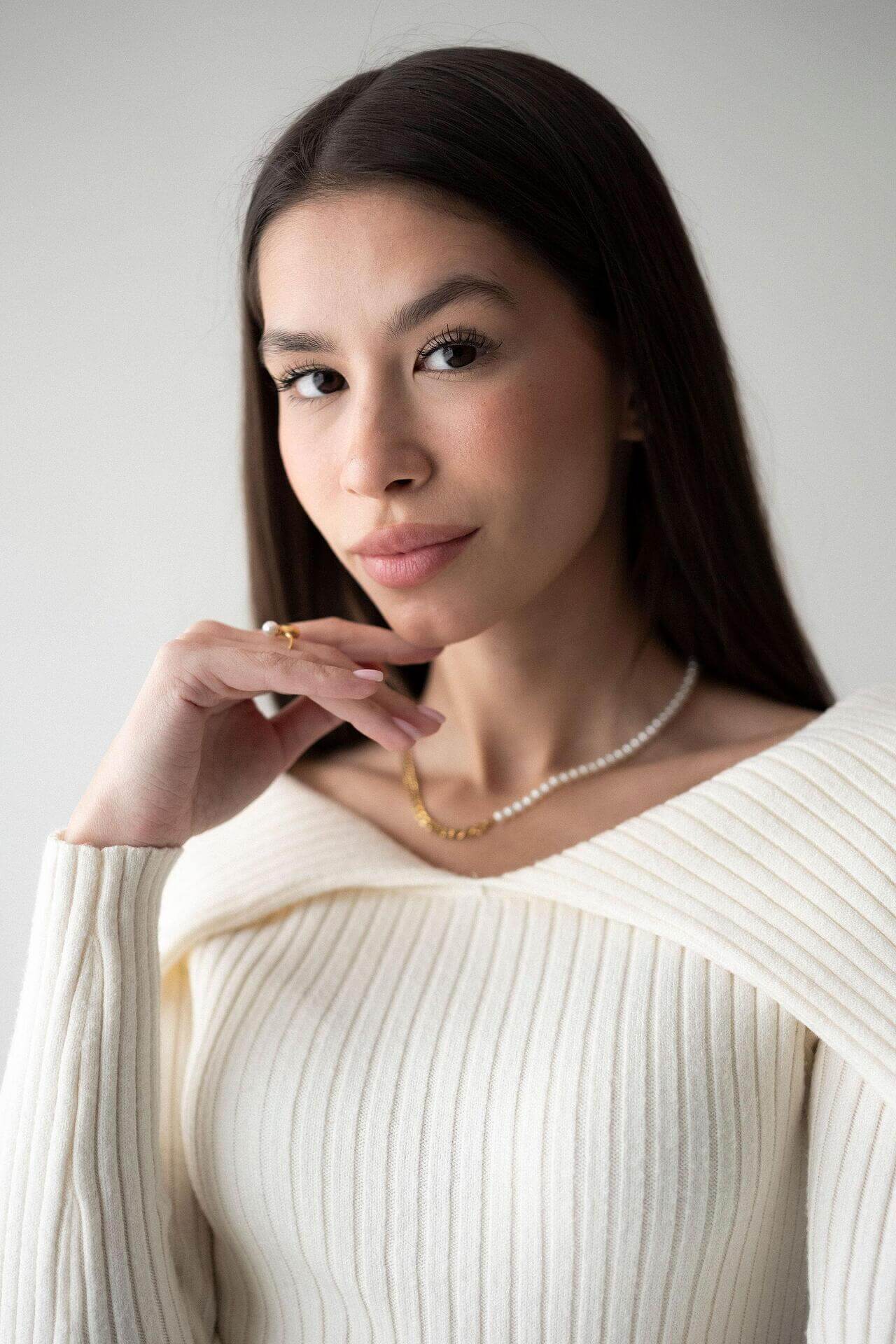 Stylish woman wearing a pearl and chain necklace with 18K gold plating, showcasing elegance and sophistication.