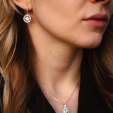 Жена с комплект обеци и колие от сребро S925 с блестящи камъни, излъчваща елегантност.