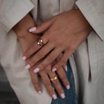 Ръце с пръстени, включително хибриден пръстен с 18К златно покритие, носени с модерен стил.