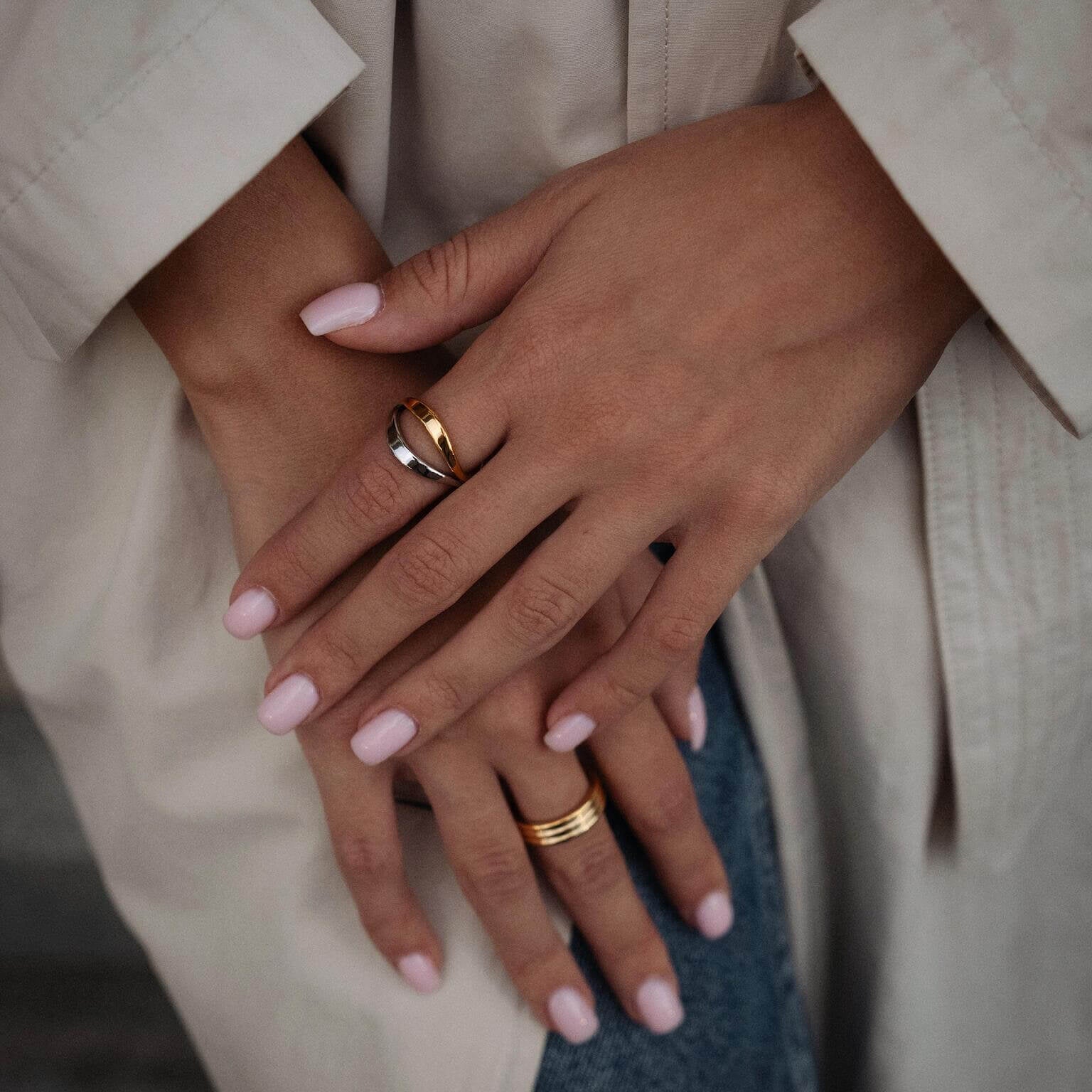 Ръце с пръстени, включително хибриден пръстен с 18К златно покритие, носени с модерен стил.