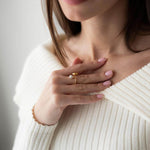Elegant woman wearing a pearl ring with 18K gold plating, styled in a cozy white sweater.