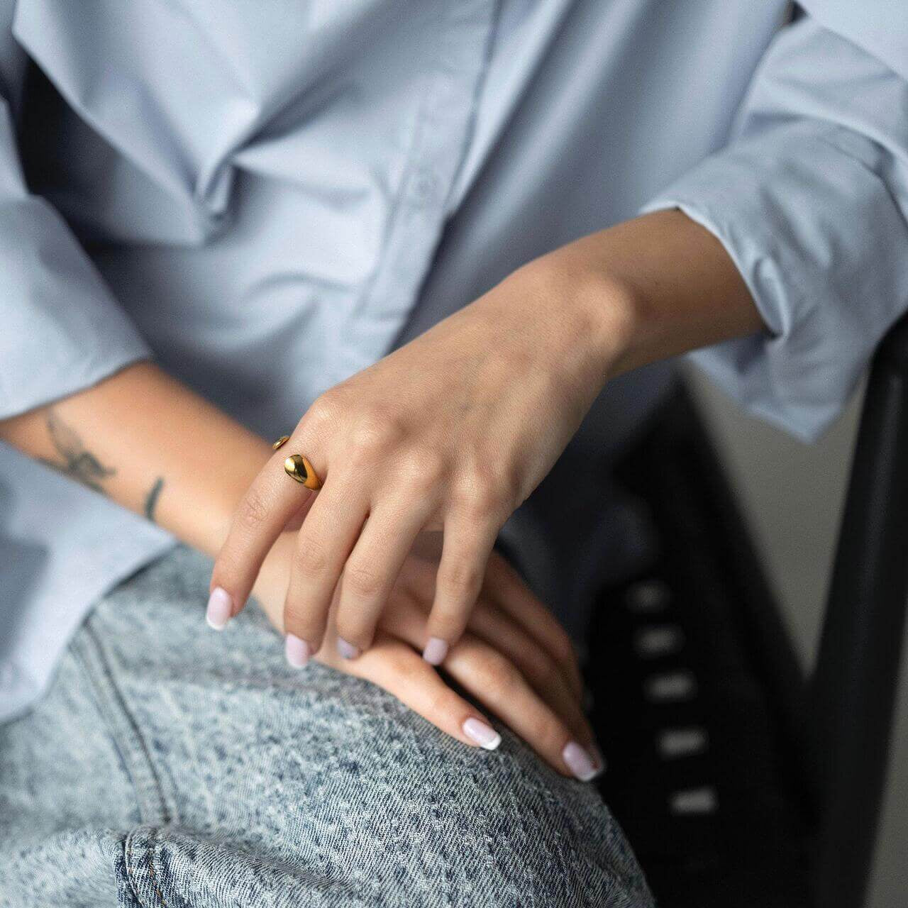 Woman wearing SOLIS ring with 18K gold plating, stylish fabric shirt, and casual jeans, showcasing luxury and warmth.