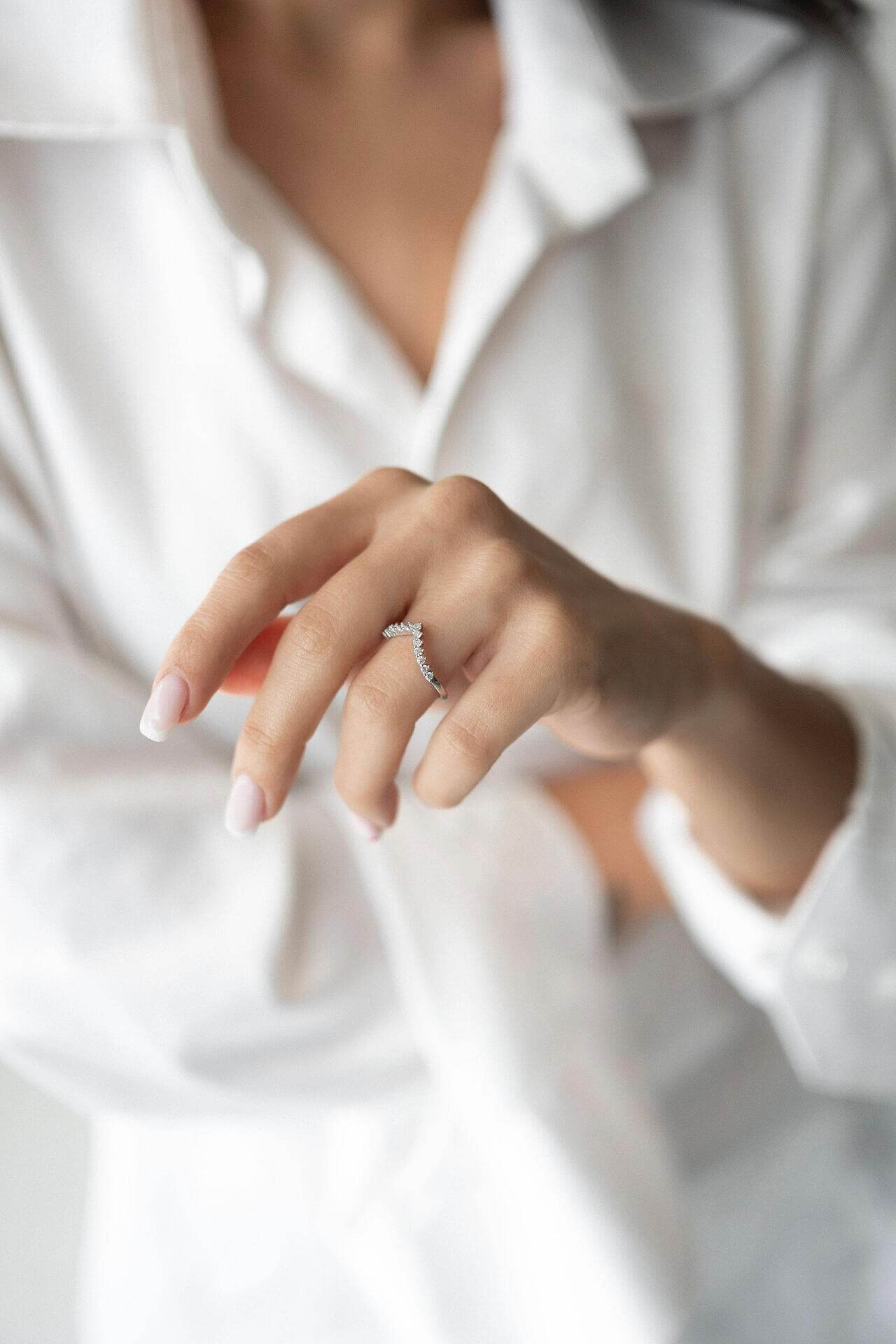 S925 silver ring with zirconia in V-shape worn on a woman's hand with a white shirt.