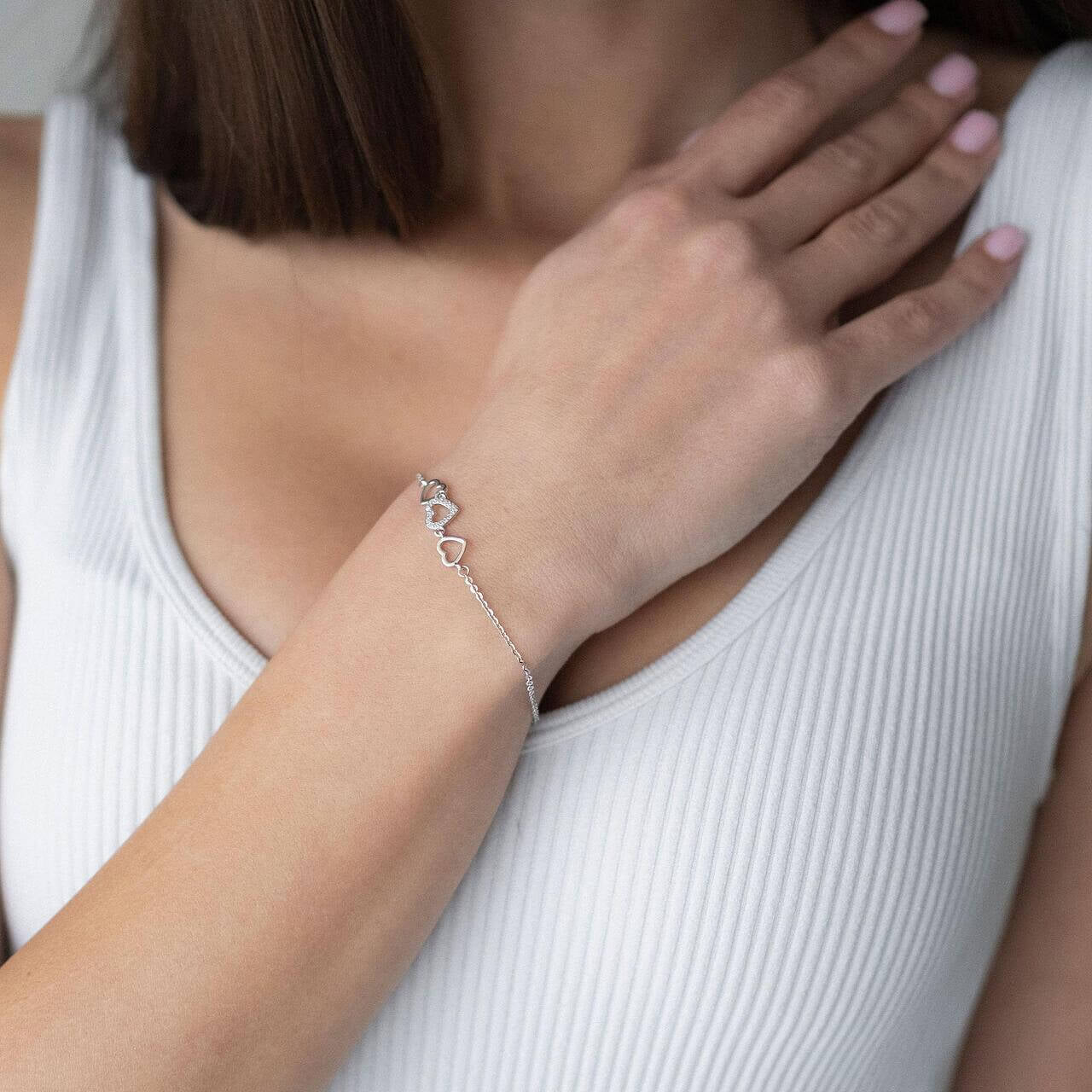 Сребърна гривна с форма на сърца, модел S925, носена от жена с изправена коса.