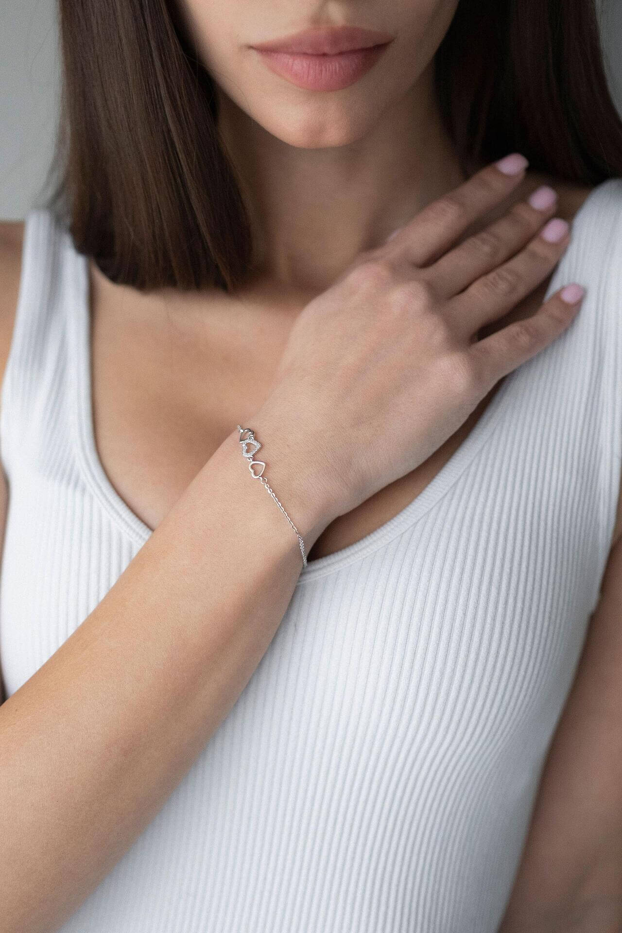 Сребърна гривна с форма на сърца, модел S925, носена от жена с изправена коса.