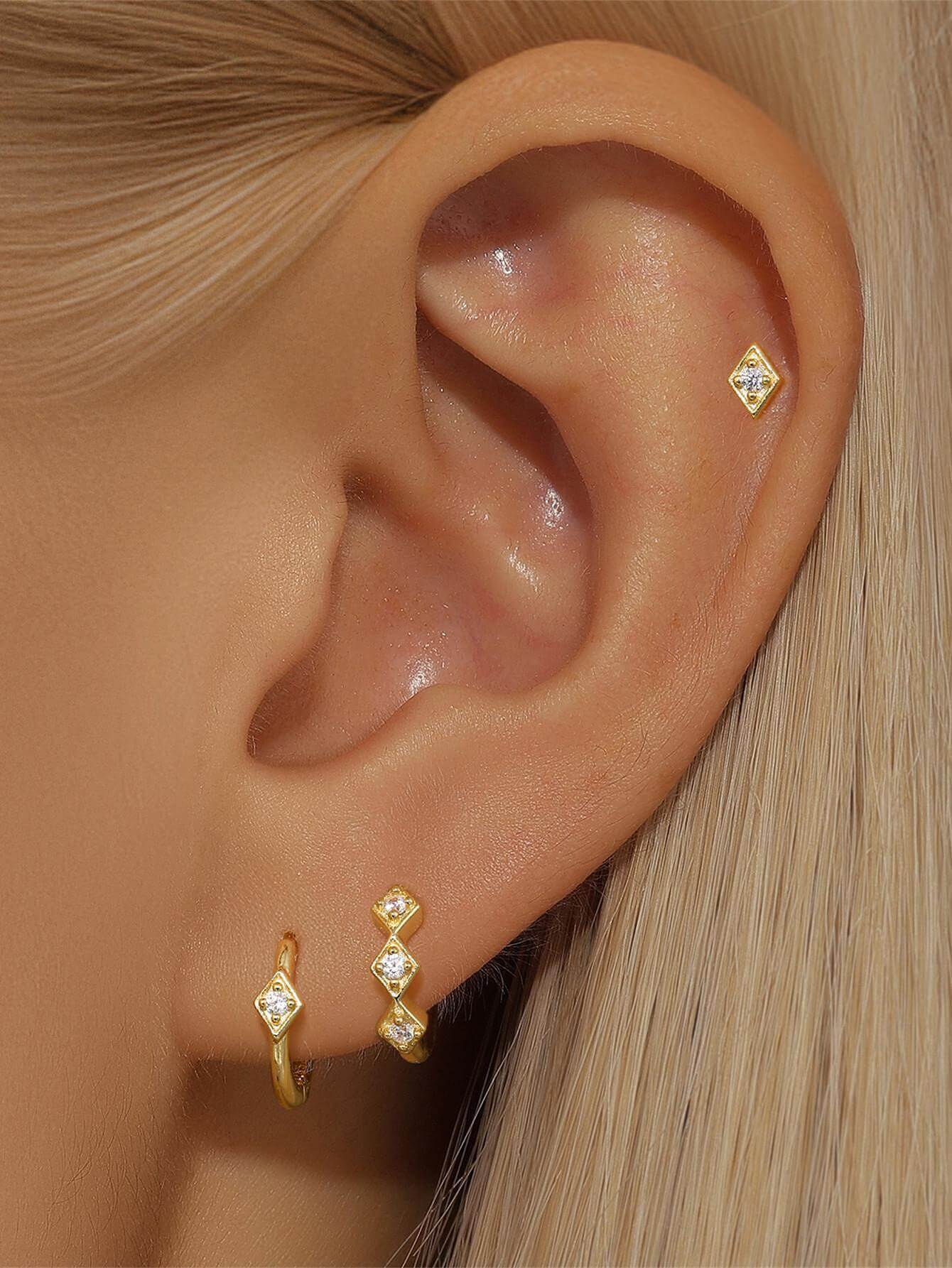 Сребърни обеци с 18K златно покритие и блестящи камъни, стилно представени на ухото.