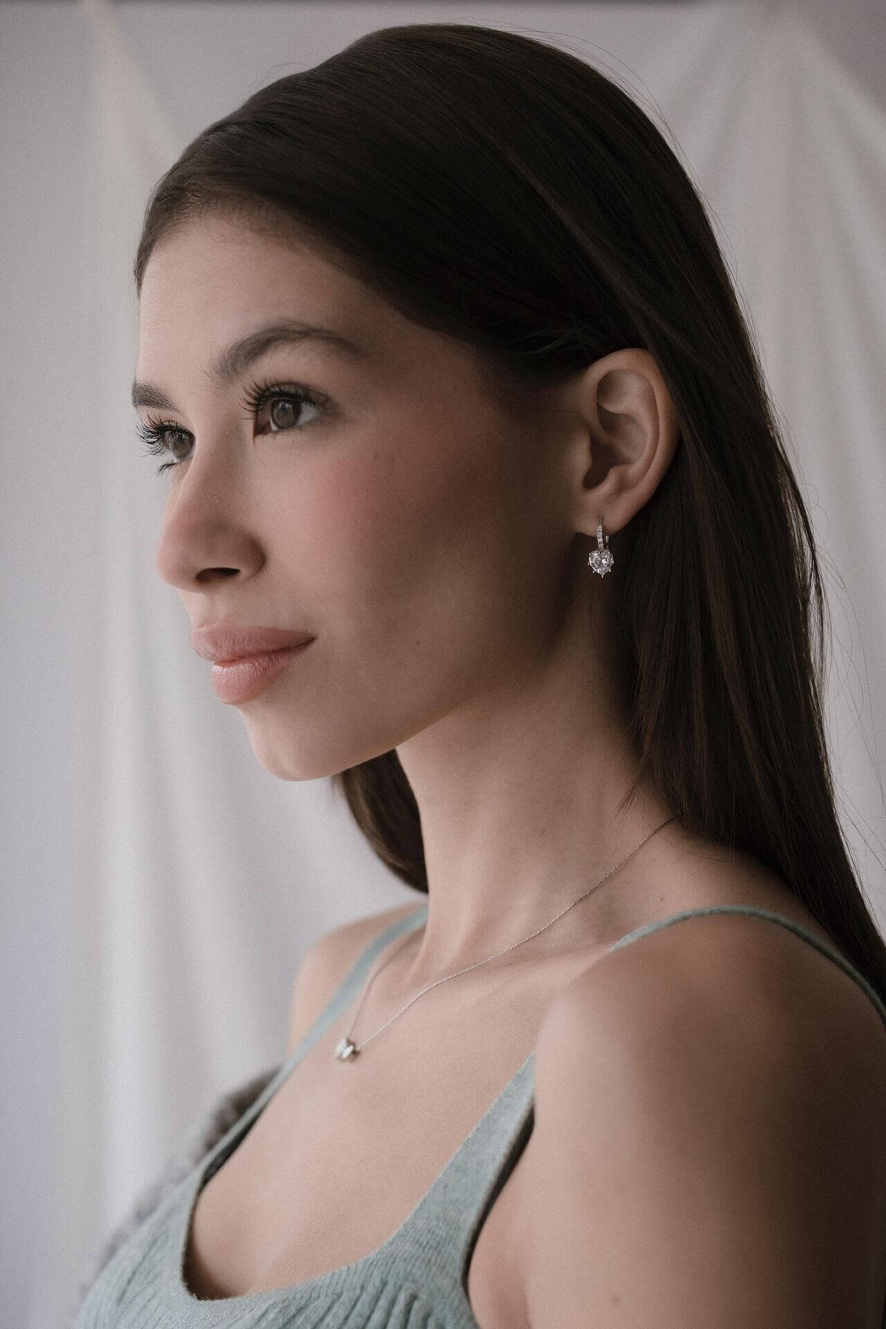 Дама с елегантни обеци във формата на сърце, с изразителен поглед и романтичен стил.