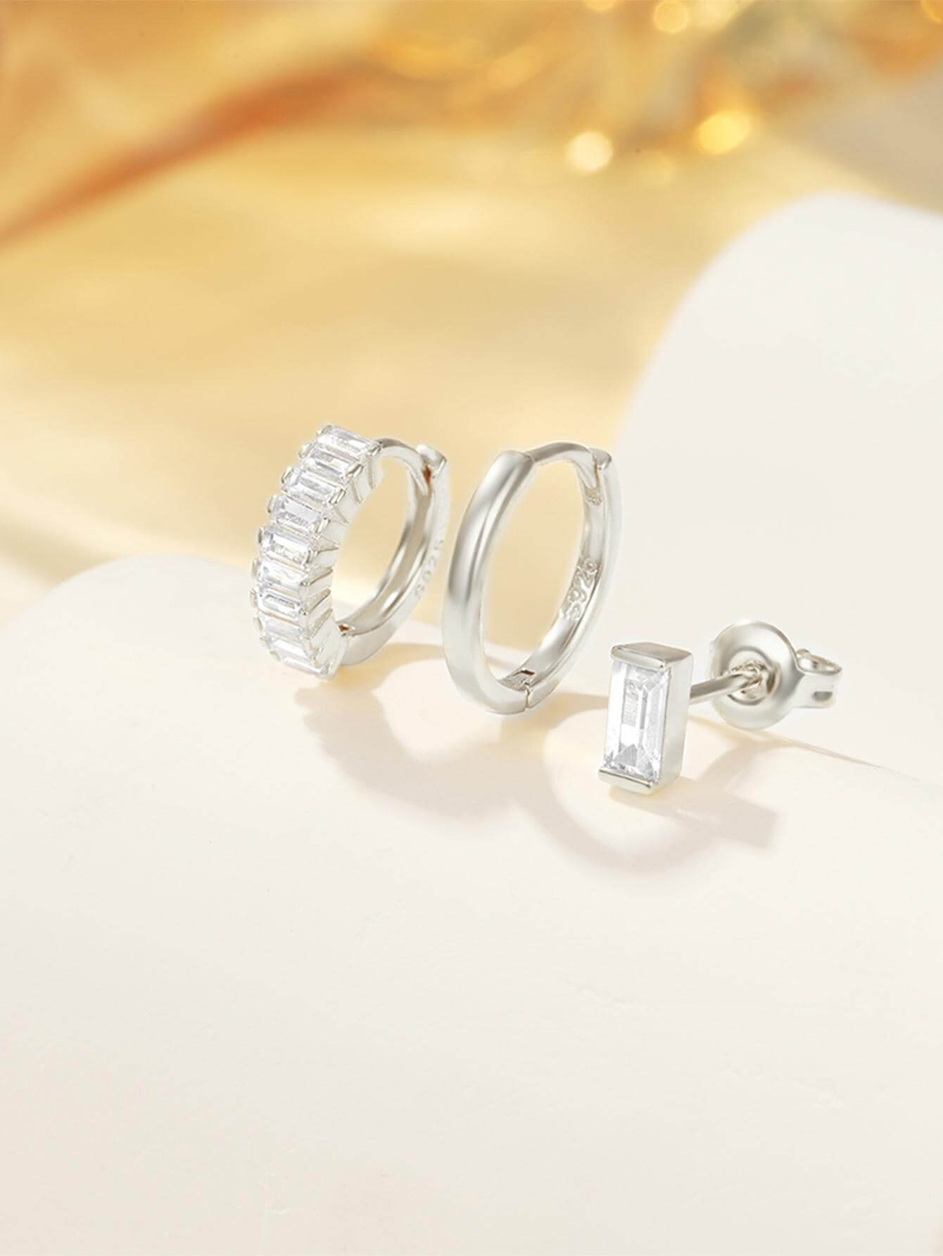 Сребърни обеци с кристали - комплект с две двойки, включващи класически и модерен стил, на светъл фон.