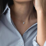 Сребърно колие с циркон на фона на жена в светло синя риза, акцентиращо на елегантност и стил.