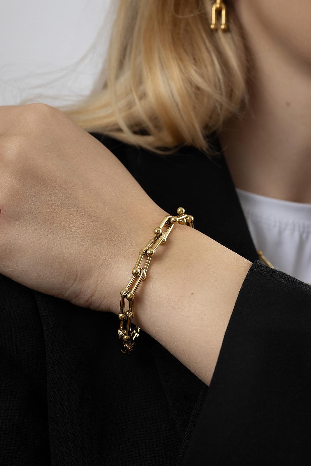 Твърда златиста гривна Signature върху ръка, изработена от медицинска стомана, елегантен и минималистичен дизайн.