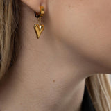 Стилистични висящи обеци с форма на златно сърце, подходящи за романтични поводи.