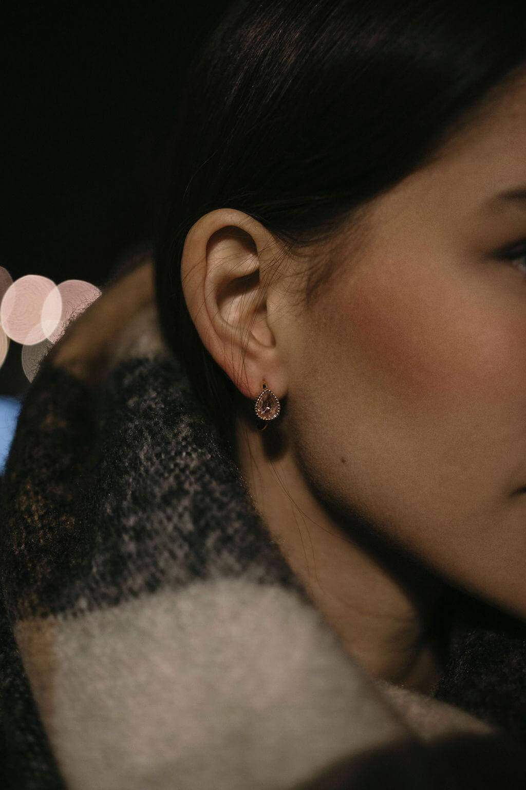 Златисти обеци с многонюансни кристали, изразяващи стил и елегантност, носени от жена с шал.