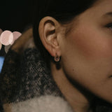 Златисти обеци с многонюансни кристали, изразяващи стил и елегантност, носени от жена с шал.