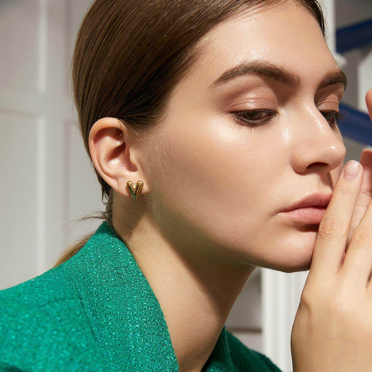 Златисти обеци във форма на сърце, стилен аксесоар, представен на модел с елегантна визия.