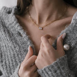 Жена с златисто колие One of a Kind, облечена в сива игла, показваща елегантен стил и индивидуалност.